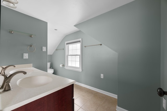 bathroom with double vanity, a sink, baseboards, tile patterned flooring, and vaulted ceiling