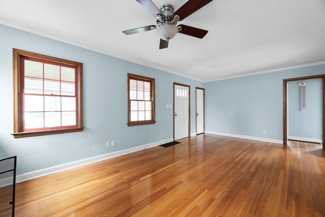 interior space with a ceiling fan, baseboards, visible vents, crown molding, and wood finished floors