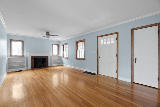 unfurnished living room featuring a ceiling fan, crown molding, a wealth of natural light, baseboards, and light wood-style floors