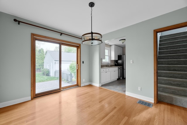 unfurnished dining area with stairs, baseboards, visible vents, and light wood-style floors