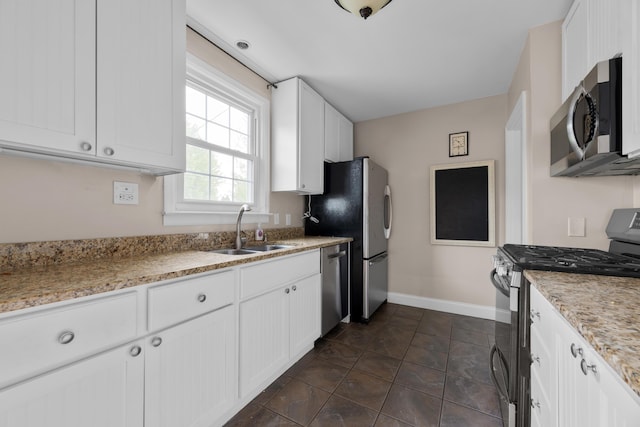 kitchen with white cabinetry, appliances with stainless steel finishes, baseboards, and a sink