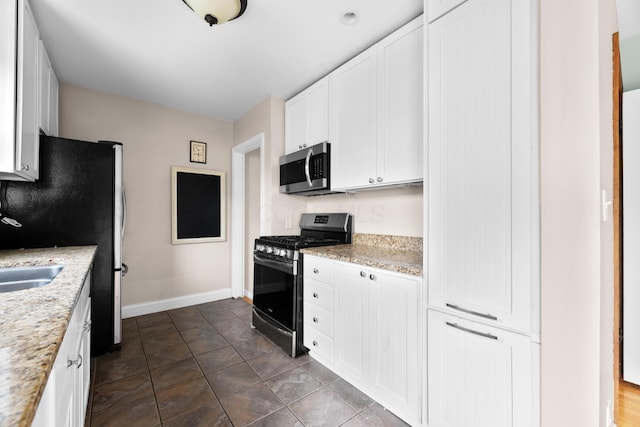 kitchen with baseboards, light stone counters, stainless steel appliances, and white cabinets