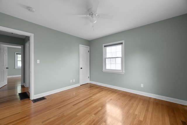 unfurnished room with light wood-type flooring, baseboards, a ceiling fan, and visible vents
