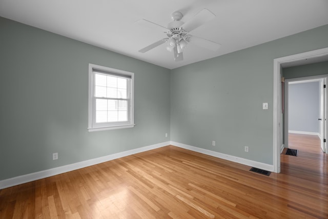 spare room featuring a ceiling fan, baseboards, visible vents, and wood finished floors