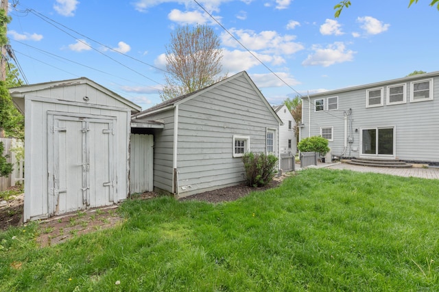rear view of property with a storage shed, an outbuilding, and a lawn