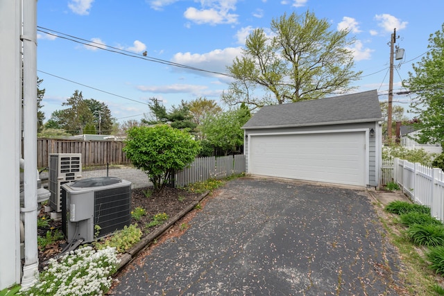 detached garage featuring central air condition unit and fence