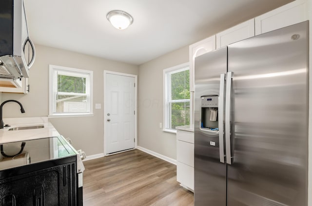 kitchen featuring appliances with stainless steel finishes, sink, light hardwood / wood-style flooring, and white cabinets