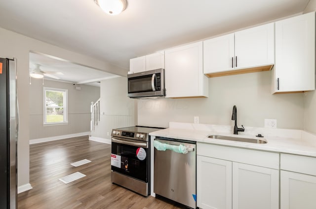 kitchen with light wood-type flooring, appliances with stainless steel finishes, sink, and white cabinets