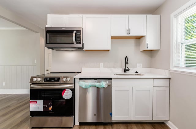 kitchen featuring sink, hardwood / wood-style flooring, stainless steel appliances, and white cabinets