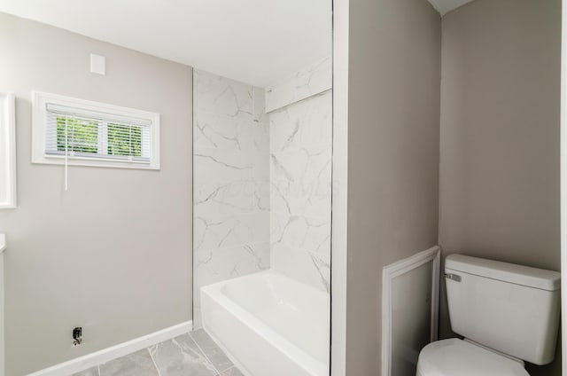 bathroom featuring tiled shower / bath combo and toilet