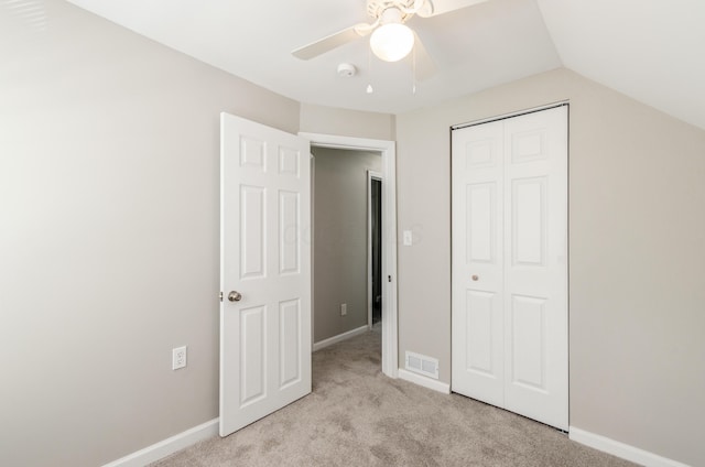 unfurnished bedroom with ceiling fan, a closet, vaulted ceiling, and light carpet