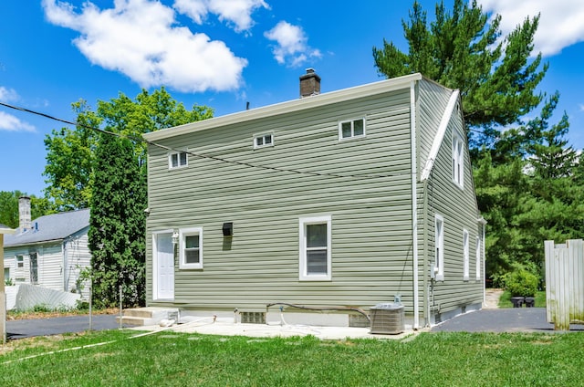 back of property featuring central AC, a lawn, and a patio area