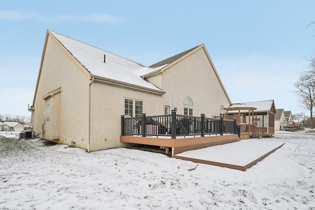 snow covered property with a wooden deck and central AC unit