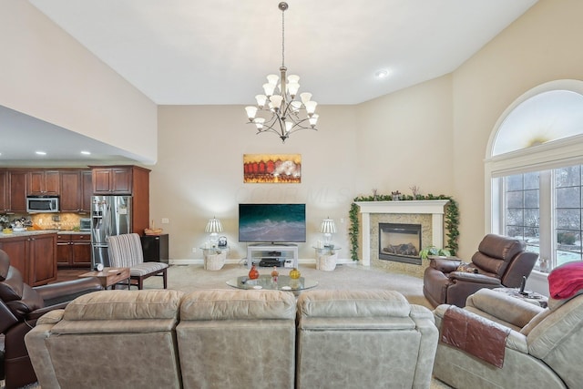 living room featuring a towering ceiling, a fireplace, a chandelier, and carpet