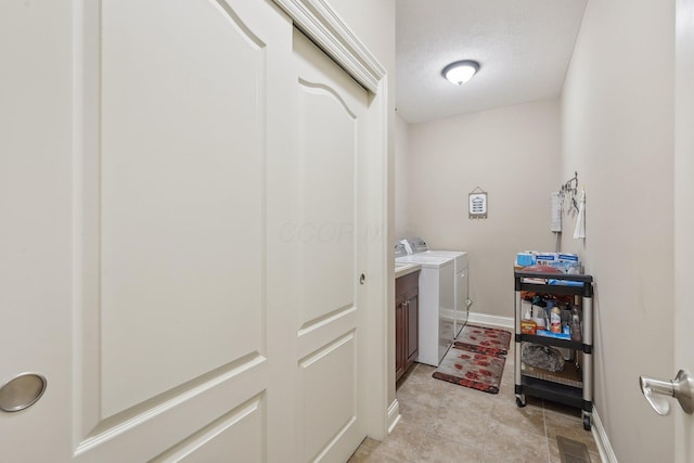 clothes washing area with cabinets, independent washer and dryer, and a textured ceiling