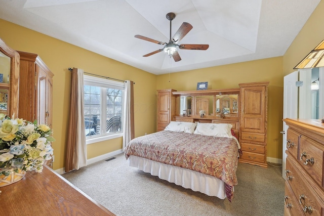 carpeted bedroom featuring ceiling fan and a tray ceiling