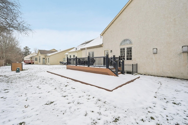 snow covered house with a wooden deck