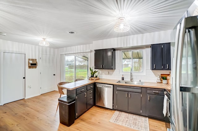 kitchen with appliances with stainless steel finishes, sink, light wood-type flooring, and plenty of natural light