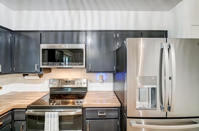 kitchen with tasteful backsplash, appliances with stainless steel finishes, and butcher block countertops