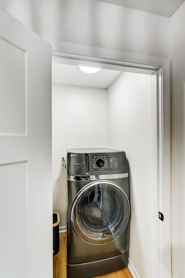 washroom with hardwood / wood-style flooring and washer / dryer