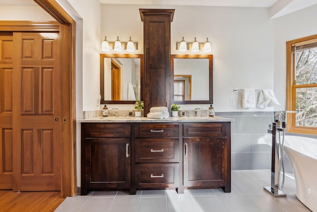 bathroom featuring tile patterned flooring, vanity, and a bath