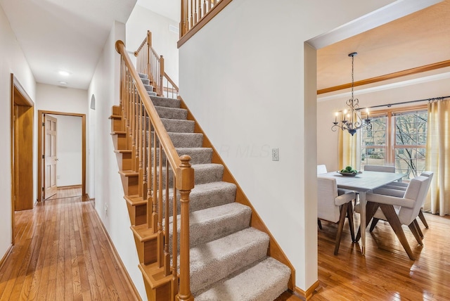 stairway with wood-type flooring and a chandelier