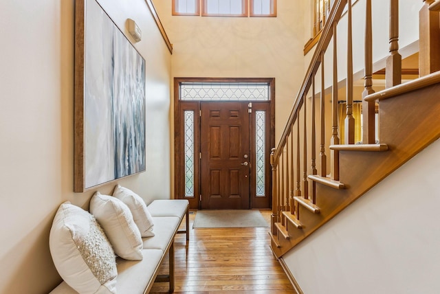 foyer entrance featuring a towering ceiling and light hardwood / wood-style flooring