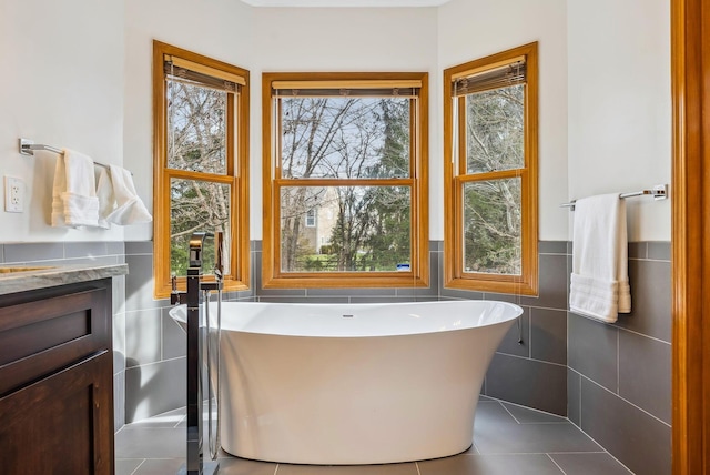 bathroom featuring vanity, tile walls, tile patterned floors, and a tub to relax in