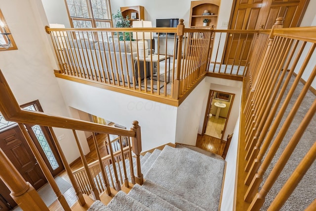 stairs featuring a towering ceiling and wood-type flooring