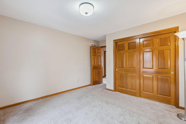 unfurnished bedroom with light colored carpet and a closet