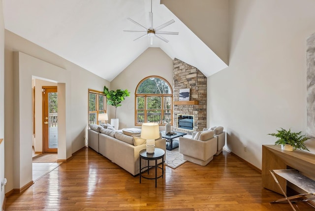 living room with a stone fireplace, high vaulted ceiling, and hardwood / wood-style flooring