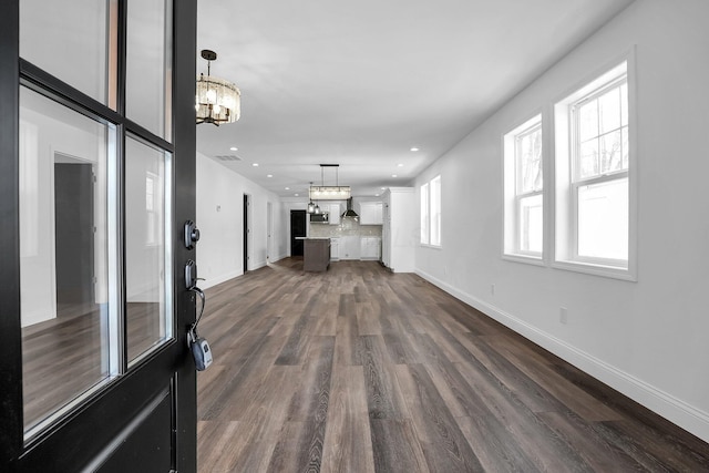 unfurnished living room featuring dark wood-type flooring and a chandelier