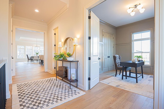 hall with crown molding, an inviting chandelier, and light hardwood / wood-style flooring