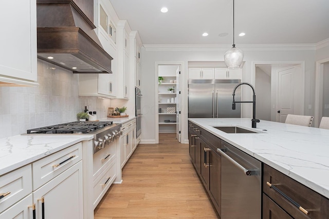 kitchen with sink, white cabinets, custom exhaust hood, stainless steel appliances, and dark brown cabinets