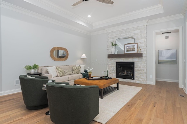 living room with hardwood / wood-style floors, crown molding, a fireplace, and a raised ceiling