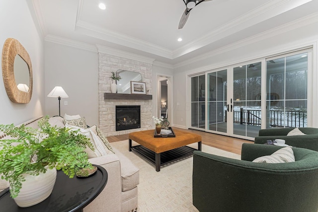 living room with crown molding, ceiling fan, wood-type flooring, and a fireplace