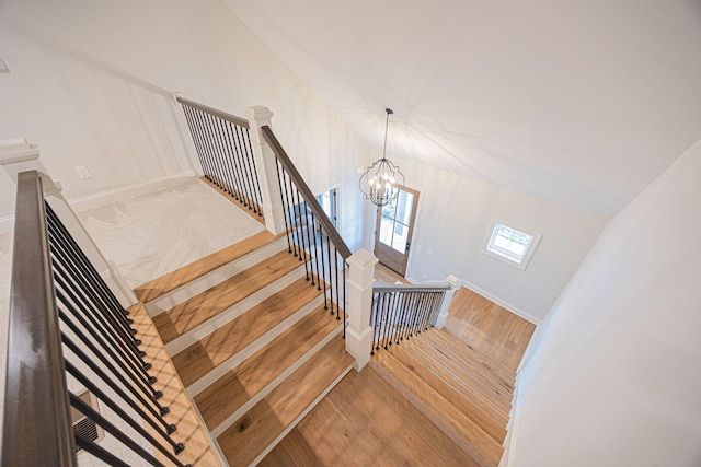 stairs with hardwood / wood-style floors and a notable chandelier