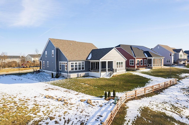 snow covered property featuring a sunroom and a lawn