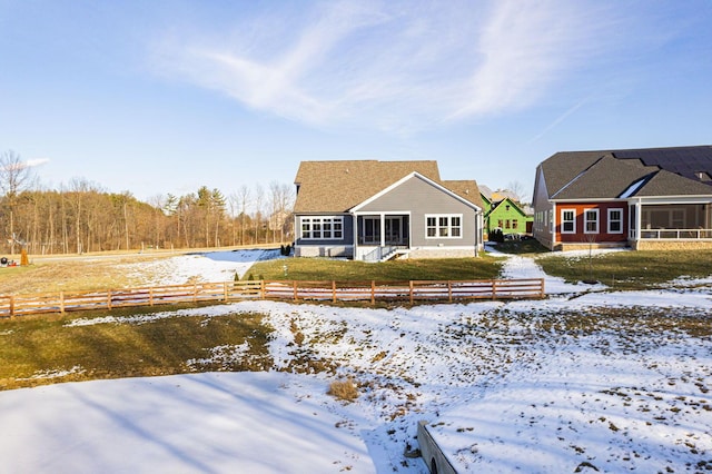 snow covered rear of property with a sunroom