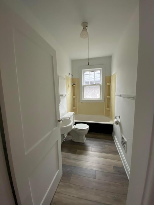 bathroom with shower / bath combination, hardwood / wood-style floors, and toilet