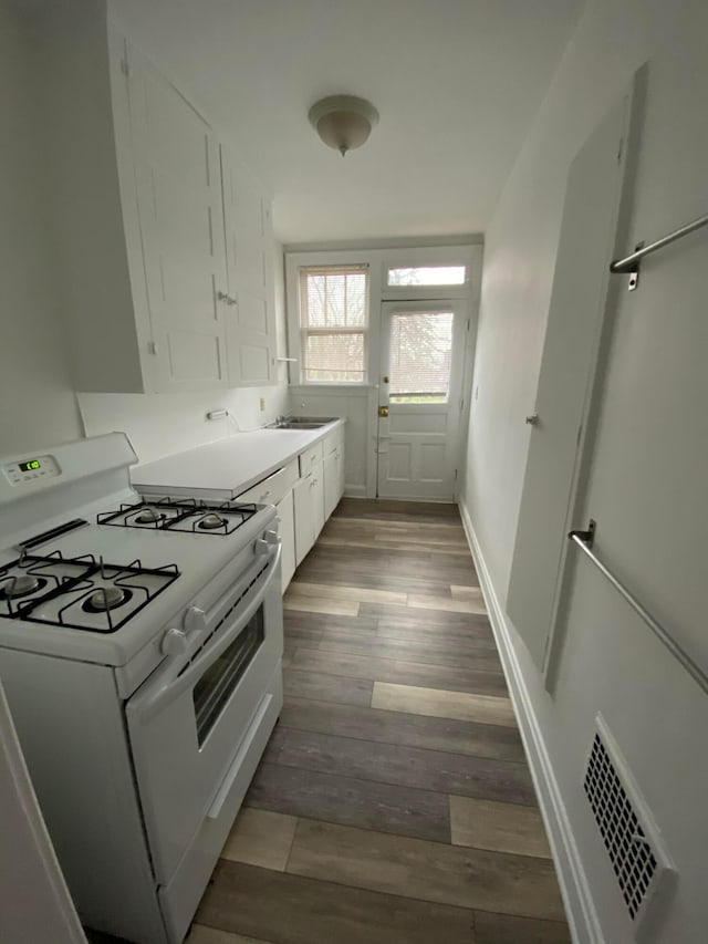 kitchen with light wood-type flooring, gas range gas stove, and white cabinets