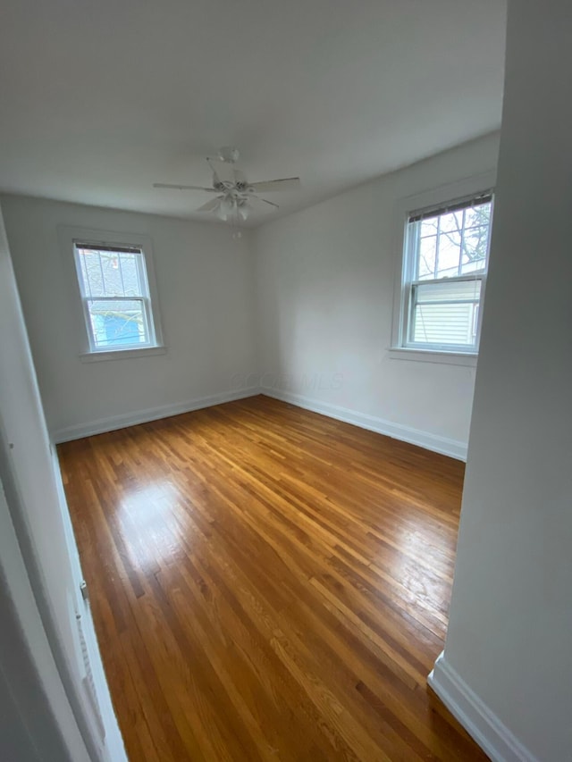 empty room with wood-type flooring, a wealth of natural light, and ceiling fan