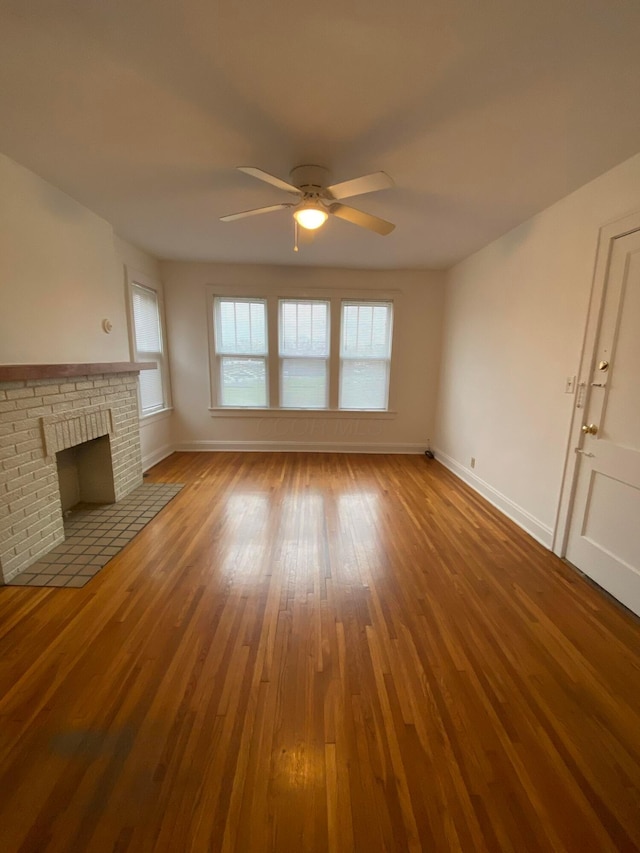 unfurnished living room with a fireplace, wood-type flooring, and ceiling fan