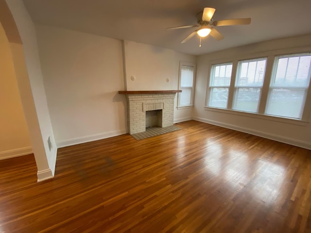 unfurnished living room with a fireplace, wood-type flooring, and ceiling fan