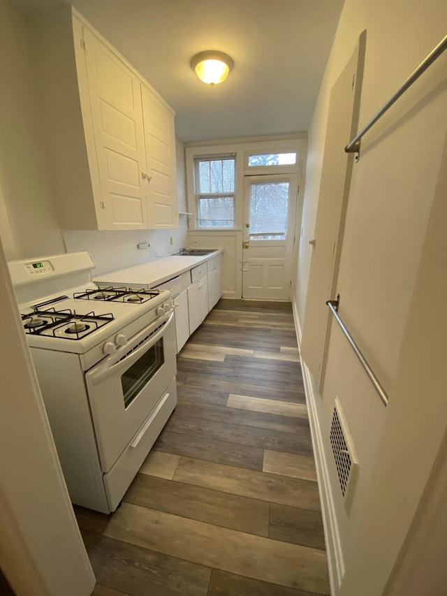 kitchen featuring sink, dark hardwood / wood-style floors, white gas stove, and white cabinets