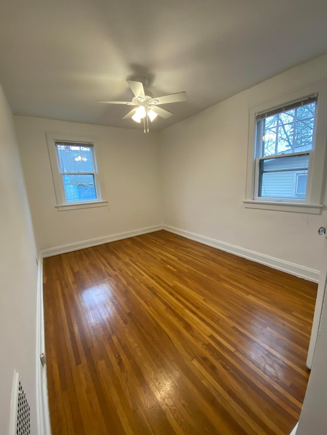 unfurnished room featuring dark wood-type flooring, ceiling fan, and a healthy amount of sunlight