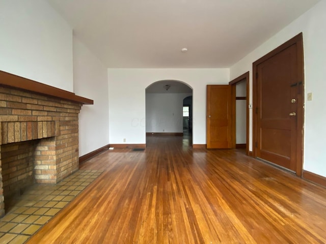 unfurnished living room with a brick fireplace and hardwood / wood-style floors