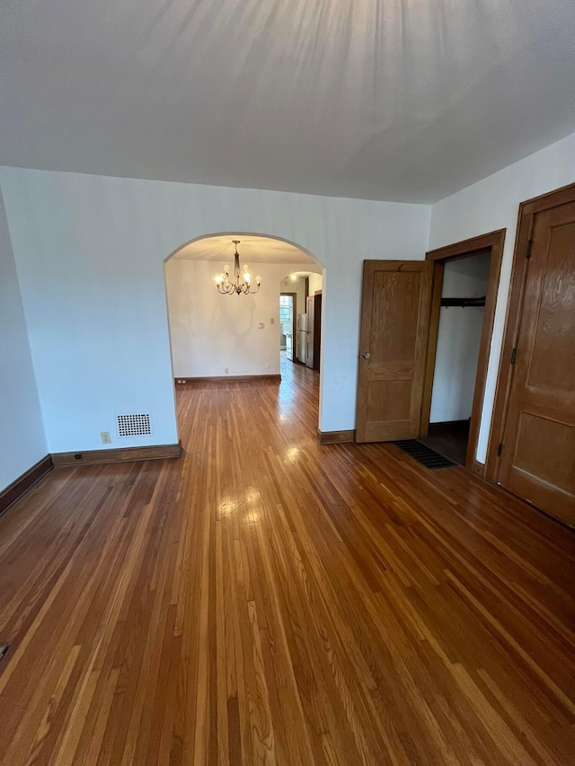 unfurnished room with an inviting chandelier and hardwood / wood-style floors