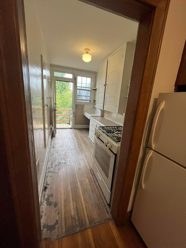 kitchen with white appliances, sink, and light wood-type flooring