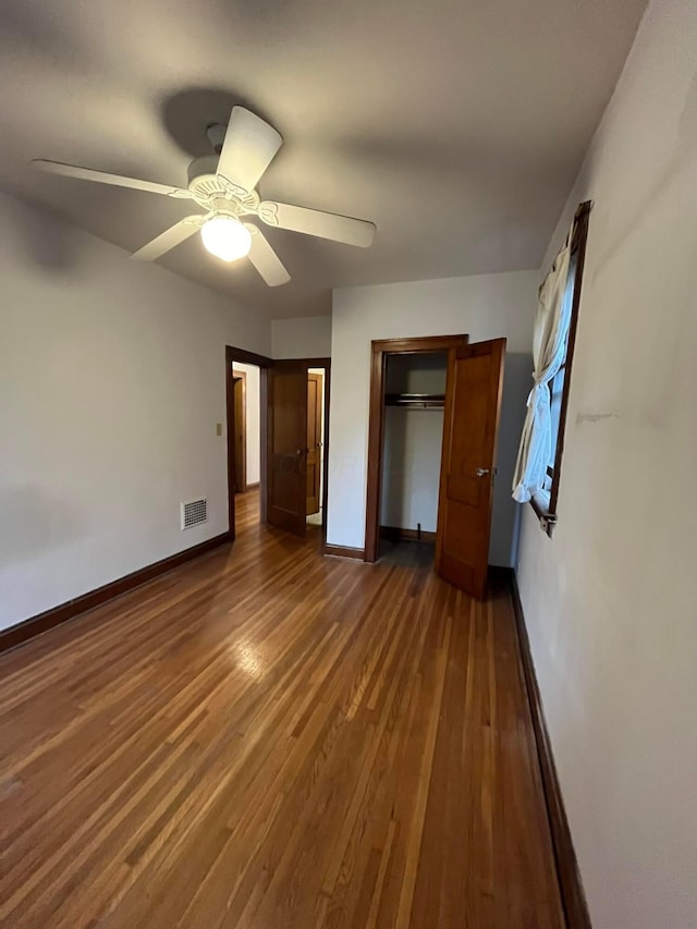 unfurnished bedroom featuring ceiling fan, dark hardwood / wood-style flooring, and a closet